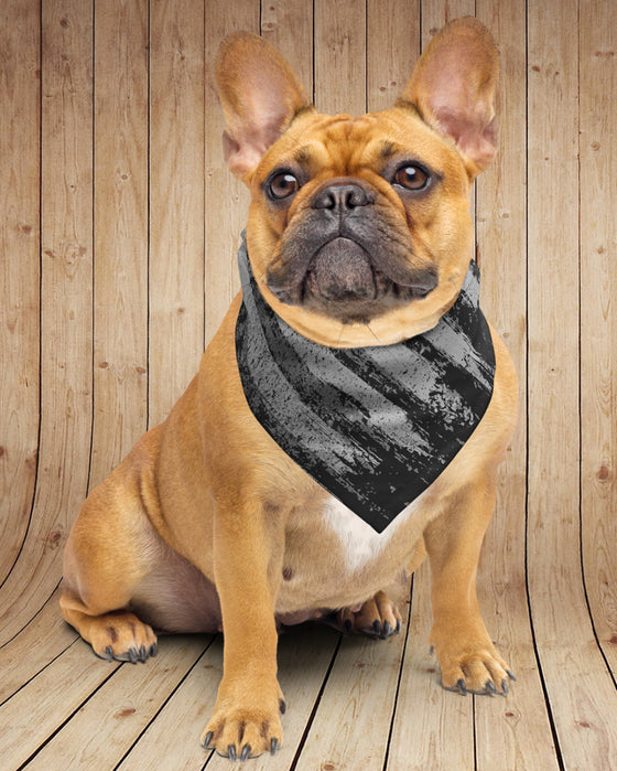 Dog wearing a black and gray striped bandana against a wooden background