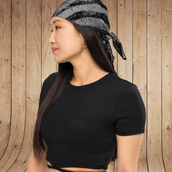 Woman wearing a black headscarf and black crop top against a wooden background