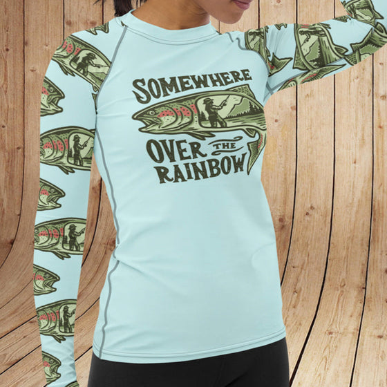 Woman wearing a light blue long-sleeve shirt with fish design and text against a wooden background