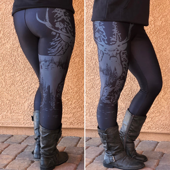 Person wearing black leggings with a woodland pattern and black boots on a textured wall background.