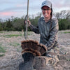 Person holding a harvested turkey in an outdoor setting