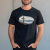 Person wearing a black t-shirt with a graphic design of a cross and landscape in camo from River to Ridge Clothing.