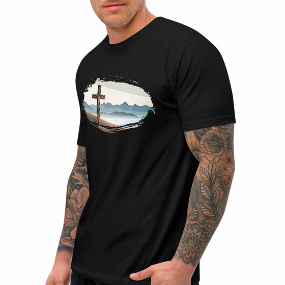 Black t-shirt with a cross and mountain design worn by a person with tattoos for River to Ridge Clothing.