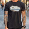Person wearing a black t-shirt with a graphic design of a cross and mountains.