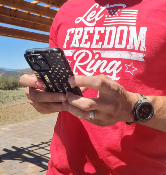 Camo Flag patriotic phone case from River to Ridge Clothing Brand, featuring the american flag in camo and black on an iphone - man holding the phone and wearing a Let Freedom Ring T shirt