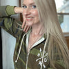 Woman wearing a camouflage hoodie with a logo, indoors.