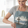 Woman in a kitchen wearing a blue apron with a cross design, mixing ingredients.