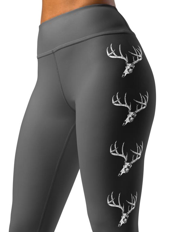 close up photo of a woman wearing grey yoga leggings with a big whitetail buck on them with the euro skull and antlers in grey