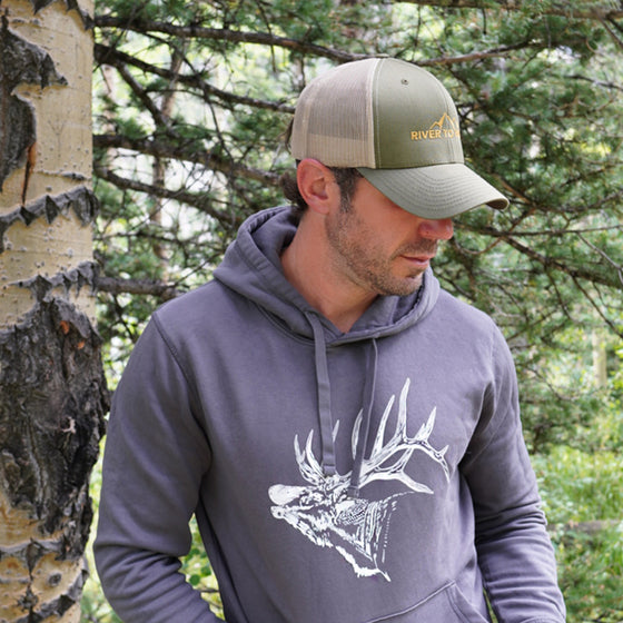 Man wearing a gray hoodie with a deer design and a matching cap in a forest setting