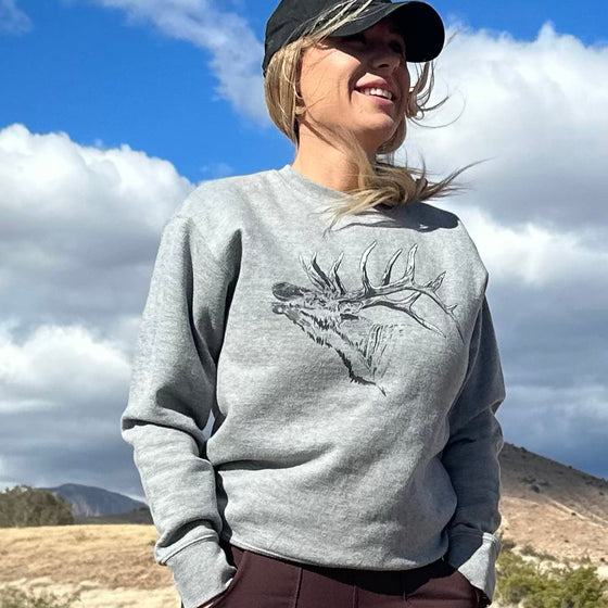 pretty woman standing on dirt road wearing elk sweatshirt, hat and work pants  from river to ridge clothing brand