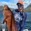 Person holding a large fish on a boat with mountains in the background
