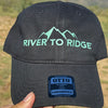 Black cap with 'River to Ridge' logo held in front of a natural landscape