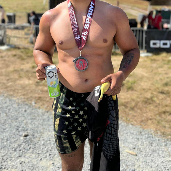 Man in Spartan Race with Medal and wearing Mens Gym Shorts with Camo American Flag Pattern from River to Ridge Clothing Brand