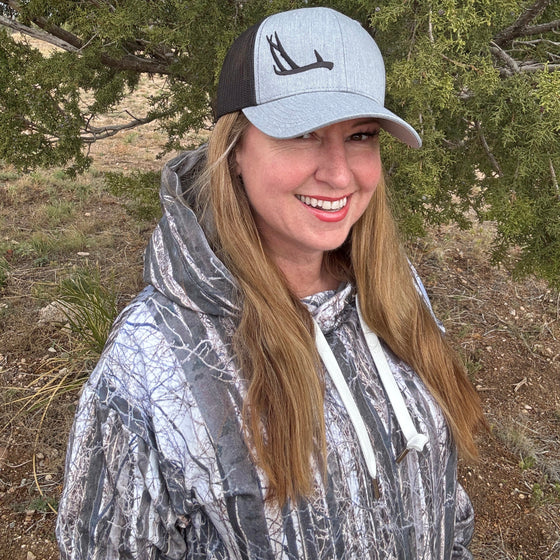 Person wearing a cap with an antler logo outdoors