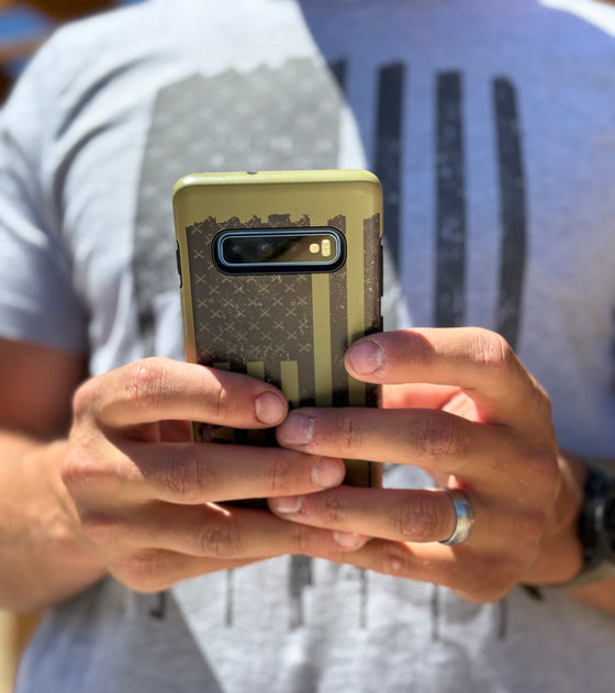 man texting on a samsung phone with a case on it with an olive tactical logo, from River to Ridge