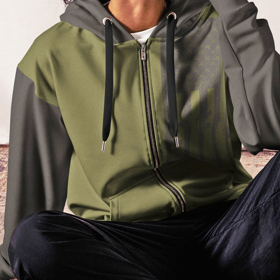 Person wearing a green and gray hoodie with a zipper, sitting on a couch.