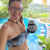 Woman holding a 'Stay Wild' cup by a pool with a scenic background