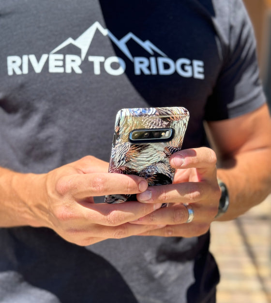 Turkey Feather pattern  case from River to Ridge Clothing Brand held by a man wearing the brands logo t shirt