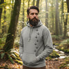 Man wearing a gray hoodie with black designs in a forest setting