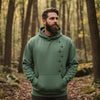 Man wearing a green hoodie standing in a forest