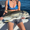 Woman holding a large fish on a boat with water in the background