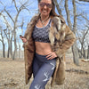 Woman in athletic wear with fur-lined coat standing outdoors in a natural setting