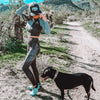 Woman in athletic wear standing on a dirt path with a dog