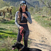 Woman in athletic wear standing on a desert path with a dog