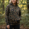 Person wearing a camouflage hoodie in a forest setting