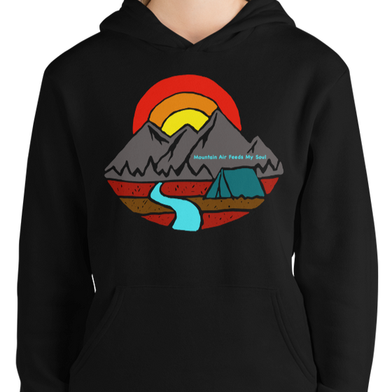 Woman wearing a hoodie in black by a brick wall and it says mountain air feeds my soul with a mountain a river and a tent on it from River to Ridge Brand