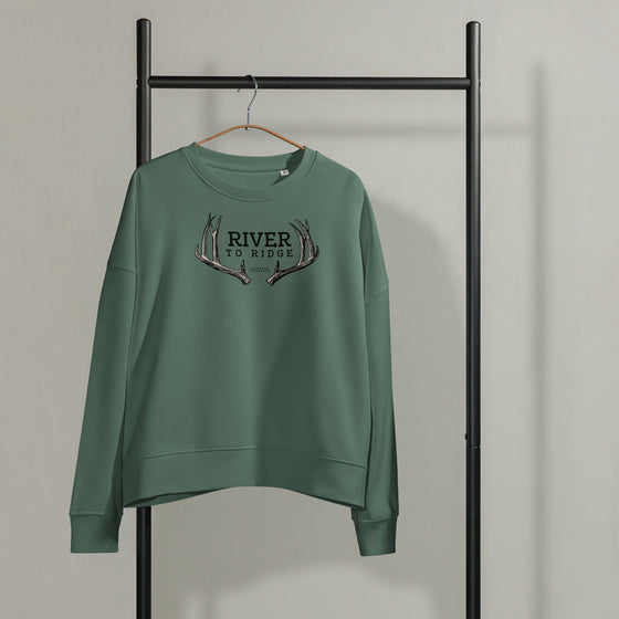 Product mockup of a River to Ridge Clothing Brand Deer Antler Womens organic cotton pullover in green hanging on a metal clothing rack